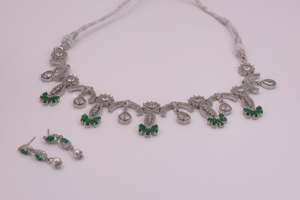 Silver necklace with green gemstones on a white background