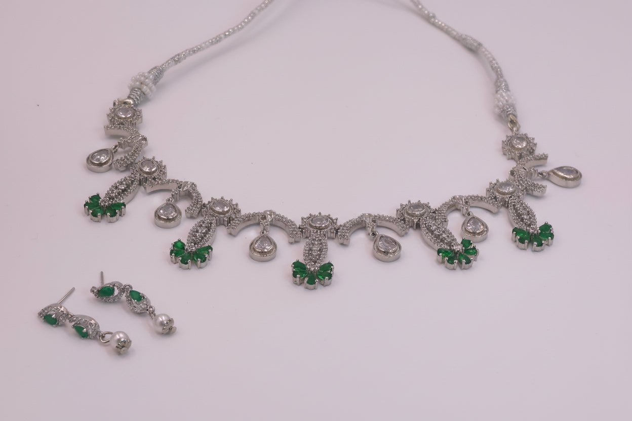 Silver necklace with green gemstones on a white background