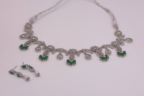 Silver necklace with green gemstones on a white background